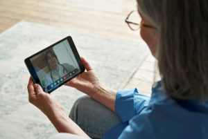戴着眼镜的患者容纳一个电子平板电脑，并在上面有一个护士的视频通话