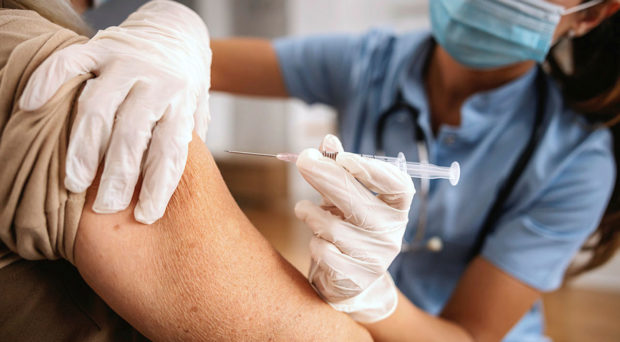 从医疗专业人员那里接收疫苗注射到上臂的患者