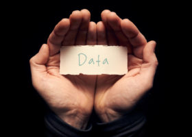 一个男人捧着一张卡片，上面手写着“数据”。