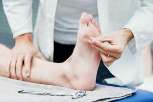 护士正在测试患者躺下时患者脚鞋底的尖锐感觉