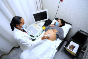 一名孕妇接受超声扫描并戴着口罩